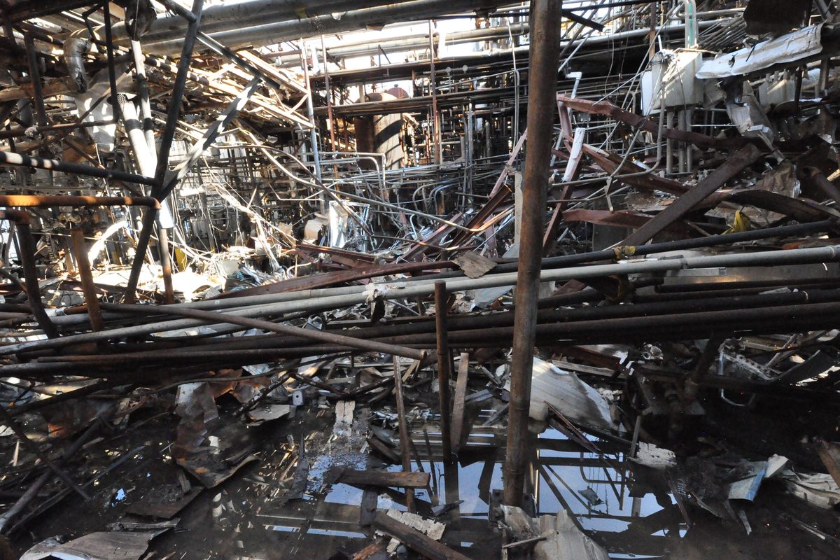 Close view of a destroyed process unit, pipework and structural steel torn apart and piled together.